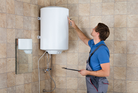 A plumber inspects a tank water heater